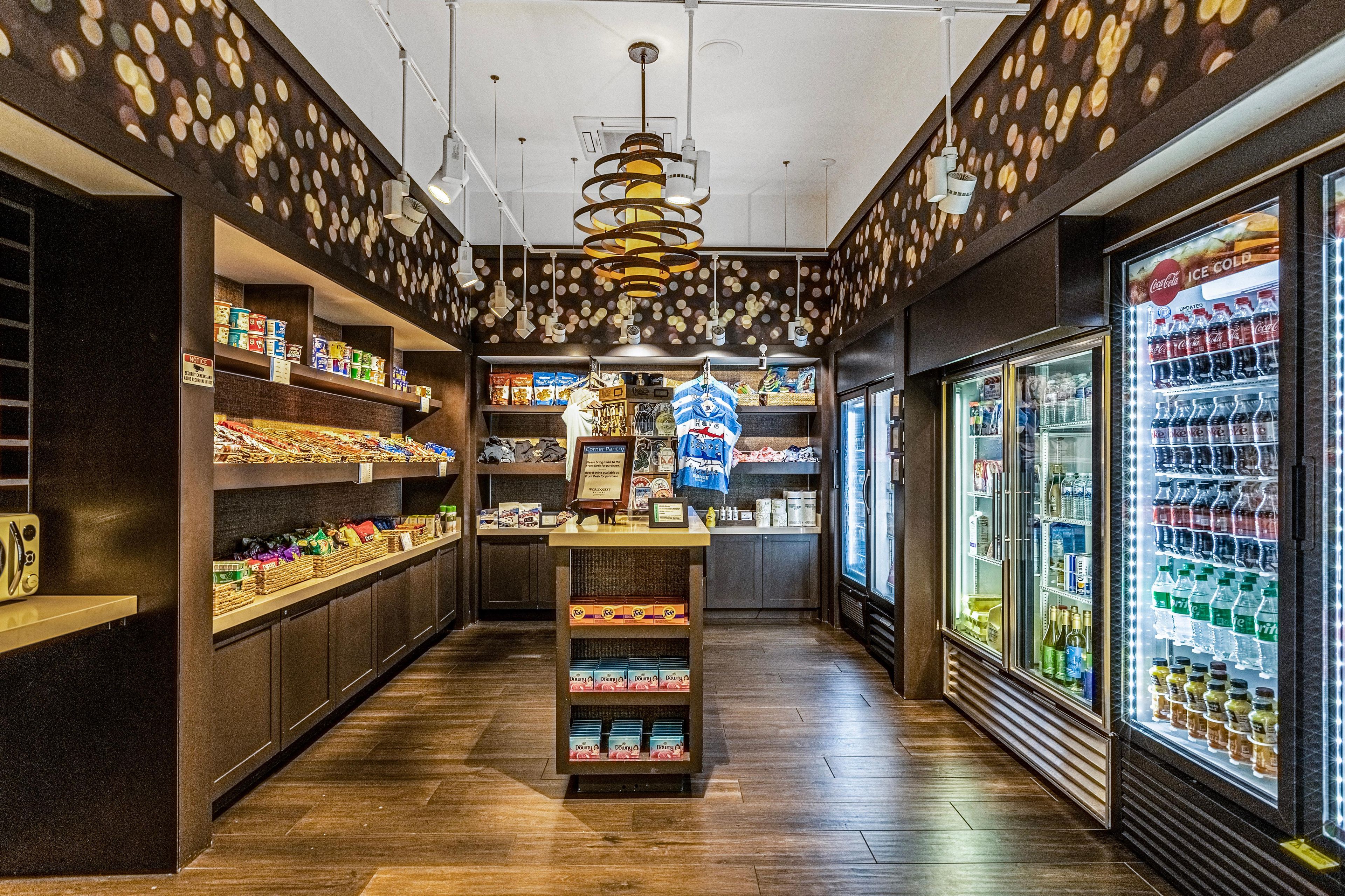 L’intérieur d’une épicerie, avec des étagères remplies de divers produits, un présentoir réfrigéré et une allée centrale.