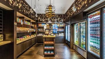 L’intérieur d’une épicerie, avec des étagères remplies de divers produits, un présentoir réfrigéré et une allée centrale.