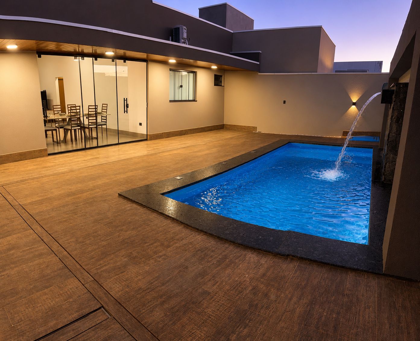Una piscina con fuente, una zona delimitada por cristales con sillas, y un diseño arquitectónico moderno.