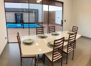 Un comedor con un separador de vidrio, una piscina y una decoración interior moderna.