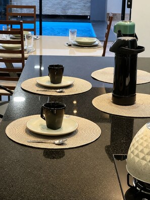 A dining table with placemats, two coffee makers, and a view of a pool. - BONITO CASA MIRRA - Cozy house in Bonito with pool and space for family. (Bonito)