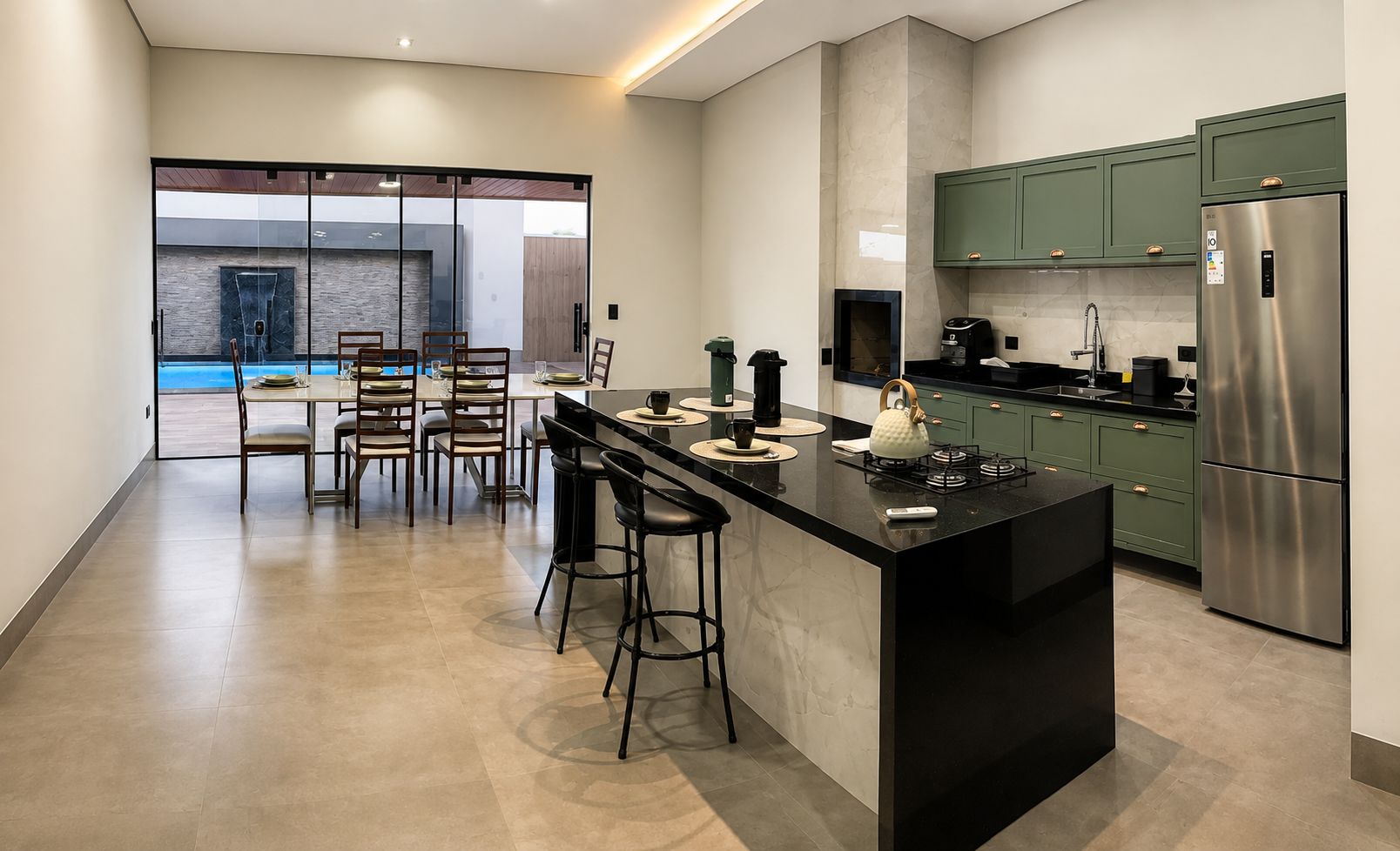 Una cocina moderna con una isla central, taburetes de bar y armarios verdes.