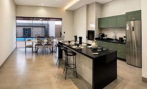 Una cocina moderna con una isla central, taburetes de bar y armarios verdes.