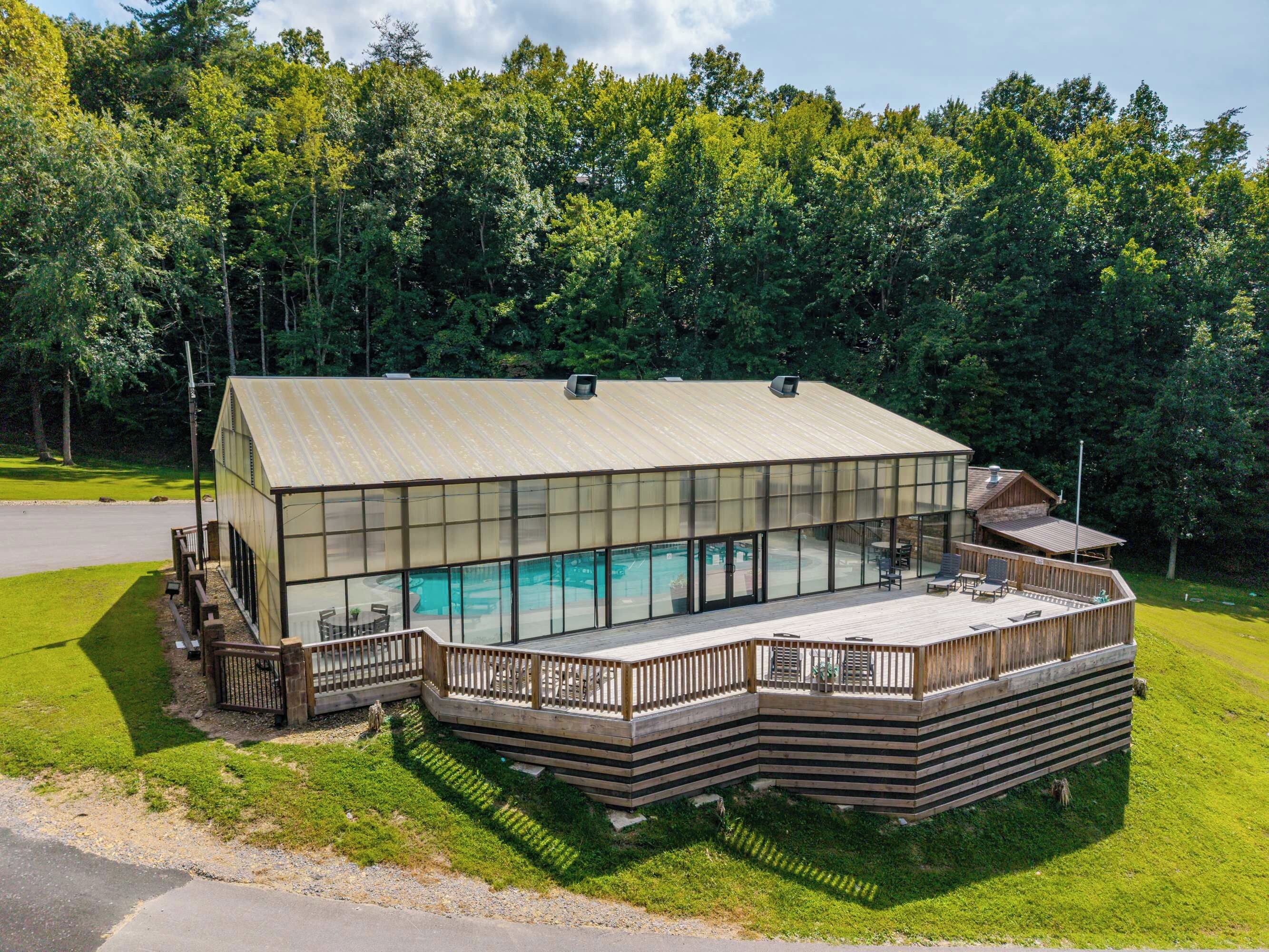 A modern house with a large glass window area, a deck, and a swimming pool.