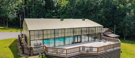 A modern house with a large glass window area, a deck, and a swimming pool.