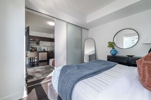 A modern bedroom with a bed, bedside table, and a mirror.