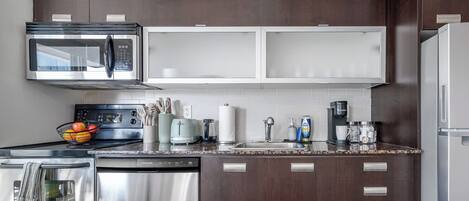 Una cocina moderna con electrodomésticos de acero inoxidable, un microondas y una cafetera.