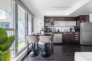 A modern kitchen with dark wood cabinets, stainless steel appliances, and a large window providing a view of the outdoors.