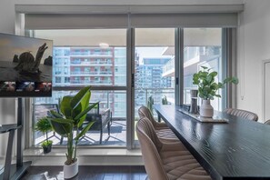 Una sala de estar moderna con un ventanal grande, una mesa de comedor y un televisor.