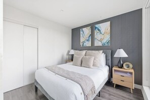 A modern bedroom with a bed, nightstands, and artwork on the wall.