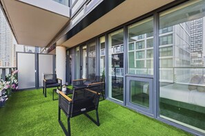 Ein moderner Außenbereich mit Kunstgrasanlage, Sitzgelegenheiten und großen Fenstern.