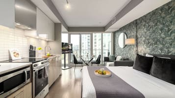 Een moderne hotelkamer met een keuken, een groot bed, een balkon met uitzicht en een televisie.