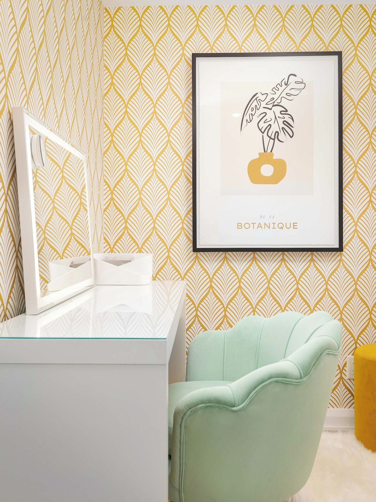 A bathroom with a white vanity, a framed botanical print on the wall, and a mint green chair.