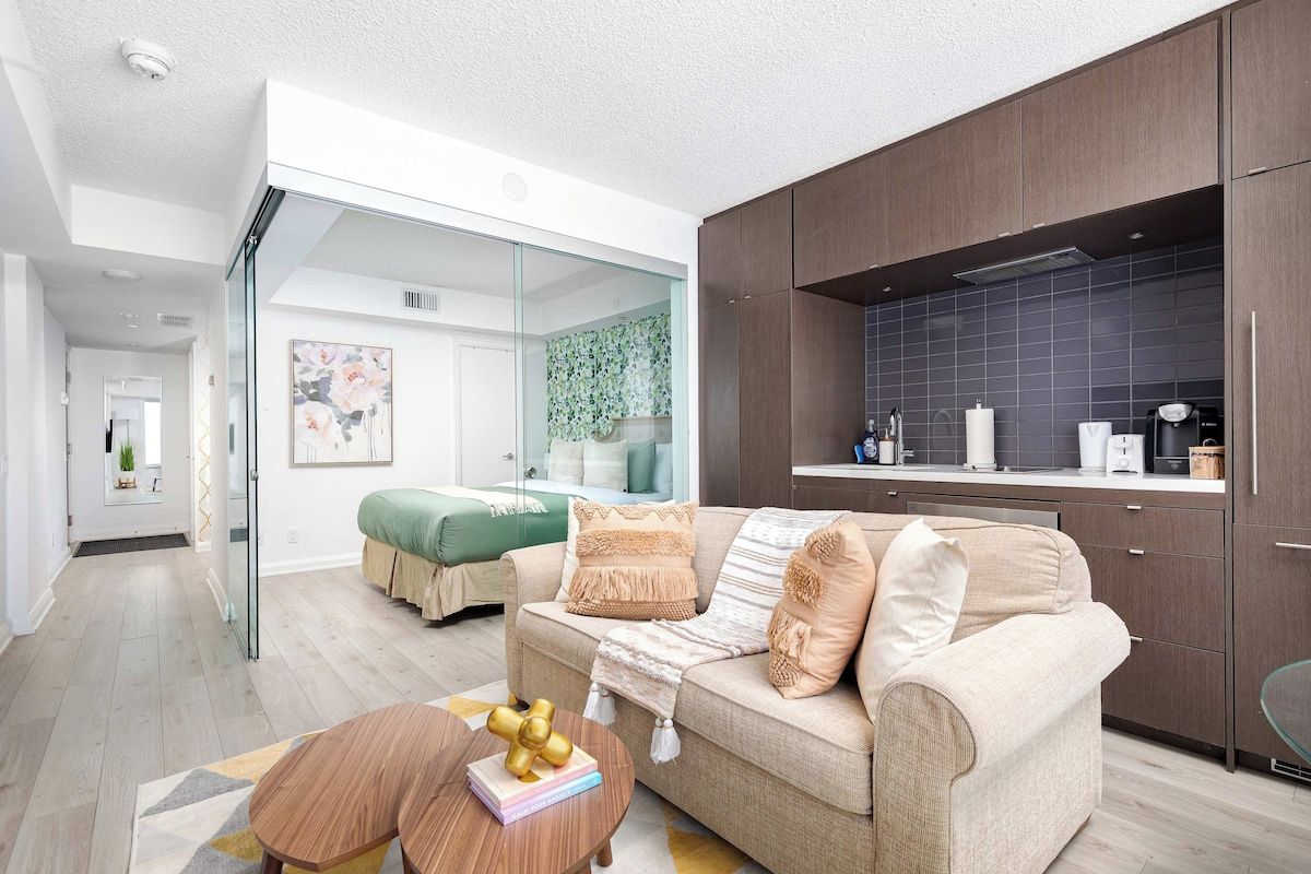 A modern living room with a sofa, a coffee table, and a kitchen area with cabinets and a countertop.