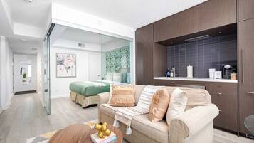 A modern living room with a sofa, a coffee table, and a kitchen area with cabinets and a countertop.