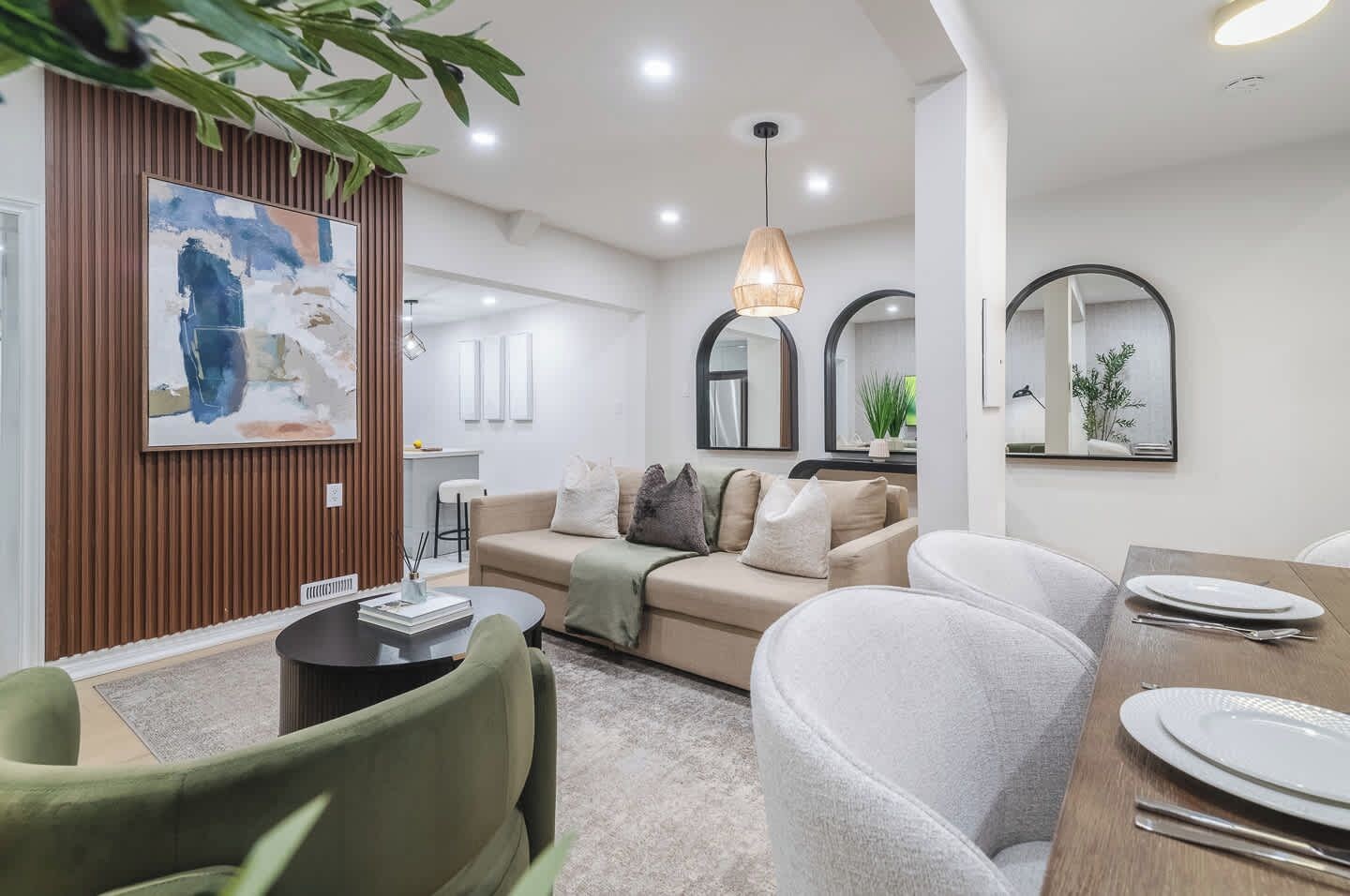 A modern living room with a sofa, a dining table set for two, and a large abstract painting on the wall.