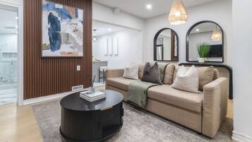 A modern living room with a sofa, a round coffee table, and a large abstract painting on the wall.