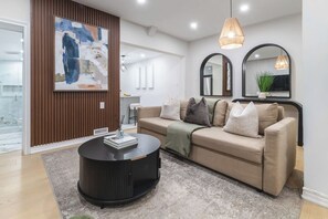 Un salon moderne avec un canapé, une table basse ronde et un grand tableau abstrait accroché au mur.