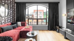 Un salon moderne avec un canapé rouge, une grande fenêtre et un téléviseur fixé au mur.