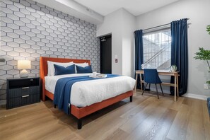 A hotel room with a bed, a desk, a chair, a nightstand, and a window with curtains. - Spacious 3BR Downtown Hub Workspace & Fast WiFi! (Toronto)