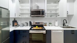 Une cuisine moderne avec des meubles blancs, un four à micro-ondes encastré, une cuisinière et un lave-vaisselle.