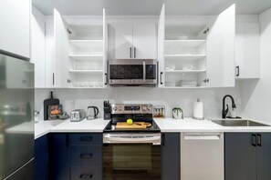 A modern kitchen with white cabinetry, a built-in microwave, a stove, and a dishwasher. - Spacious 3BR Downtown Hub Workspace & Fast WiFi! (Toronto)