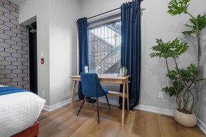A bedroom with a bed, a desk with a chair, a window with curtains, a potted plant, and a patterned wall. - 3BR Downtown Toronto Stay near Chinatown & Kensington Market (Toronto)