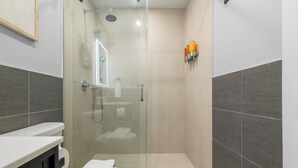 Une salle de bain moderne avec une douche à parois de verre, des toilettes et un lavabo.