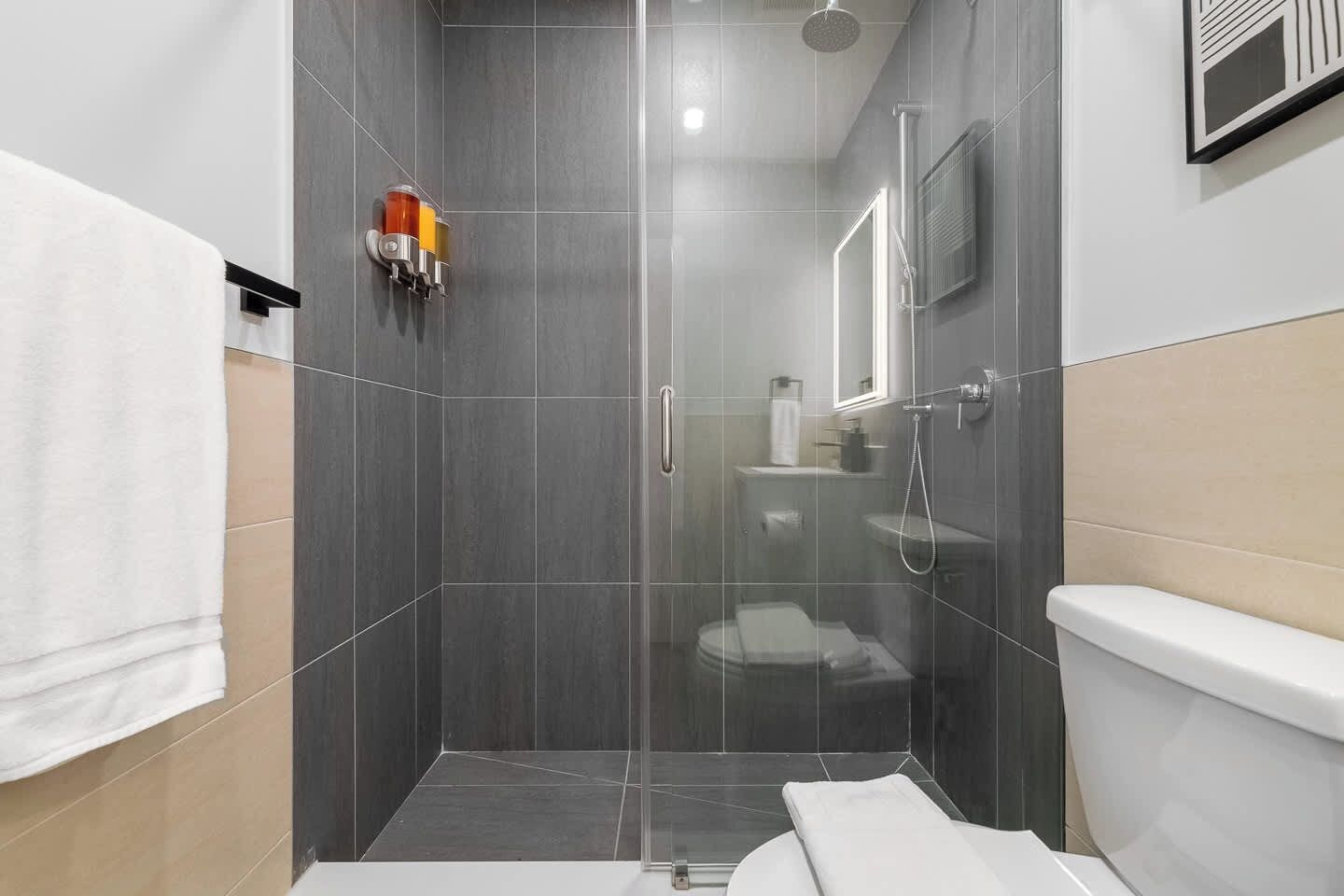 A modern bathroom with a glass-enclosed shower, a toilet, and a sink.
