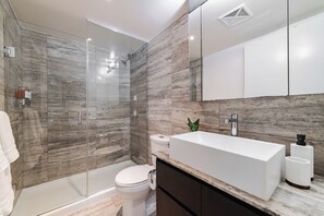 Une salle de bain moderne avec une douche à parois de verre, un lavabo blanc et des toilettes.