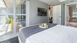 Una habitación de hotel moderna con una cama grande, un área de comedor y vistas al exterior.