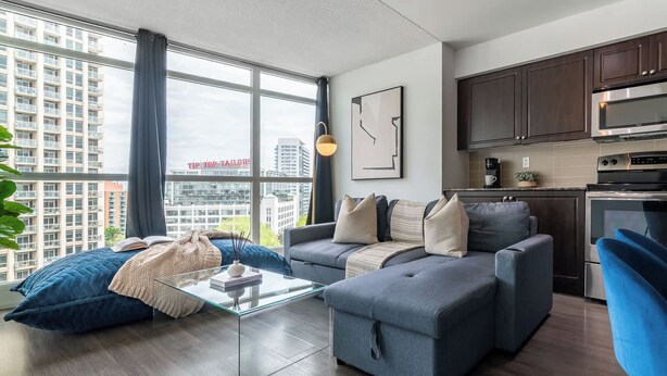 Ein modernes Wohnzimmer mit einer Couch, Hocker und einem Glastisch.