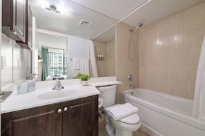 A modern bathroom with a bathtub, toilet, and sink. - Spacious 3BR condo with patio & free parking (Toronto)