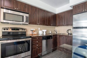 A modern kitchen with stainless steel appliances, wooden cabinets, and a glass backsplash.