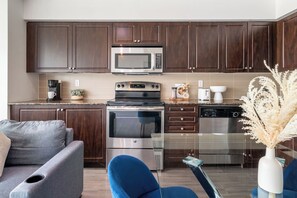 A modern kitchen with dark wood cabinets, stainless steel appliances, and a glass backsplash.