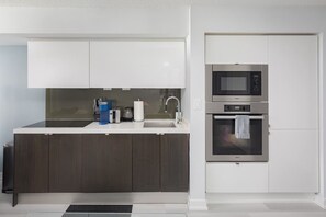 A modern kitchen with dark wood cabinets, a white countertop, a built-in microwave, and an oven. - Stylish 2BR Downtown Skyline Views & Free Parking | Parking Available (Toronto)