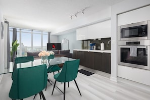 A modern kitchen with white cabinets, a built-in microwave, and an oven. - Stylish 2BR Downtown Skyline Views & Free Parking | Parking Available (Toronto)
