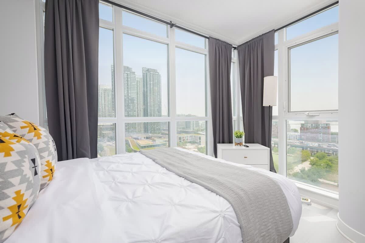 Une chambre d’hôtel avec un grand lit, une table de chevet, une lampe et une vue sur la ville.