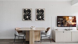 Uma sala de jantar moderna com uma mesa de madeira, quatro cadeiras e duas obras de arte abstratas penduradas na parede.