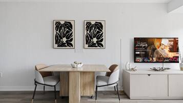 Un comedor moderno con una mesa de madera, cuatro sillas y dos obras de arte abstracto colgadas en la pared.