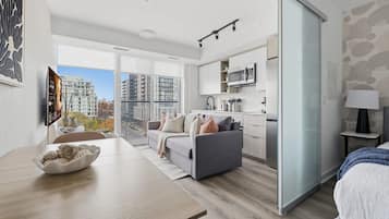 Un apartamento moderno con comedor, sofá, cocina y un amplio ventanal con vista a la ciudad.