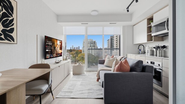 Apartamento moderno com área de jantar, sofá, cozinha e grandes janelas com vista para a cidade.