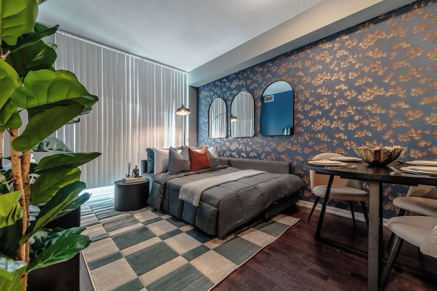 A modern bedroom with a large bed, a dining table, and a decorative mirror.