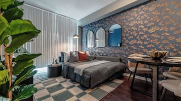 A modern bedroom with a large bed, a dining table, and a decorative mirror.