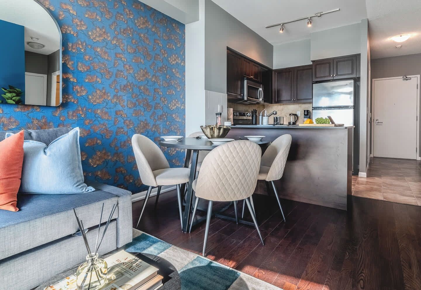Een moderne keuken met donkere kastjes, een centraal eiland en een eetgedeelte met twee stoelen.