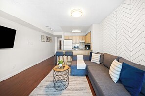 A modern living room with a sofa, a coffee table, and a TV mounted on the wall.