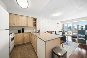 Ett modernt kök med en central köksö, träskåp och utsikt över staden genom stora fönster.