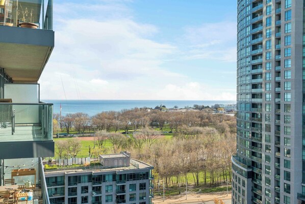 A high-rise building with a view of a park and a body of water.