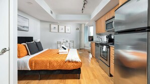 A modern hotel room with a bed, a kitchenette, and a bathroom. - Bright Waterfront Studio Steps to DT Toronto (Toronto)
