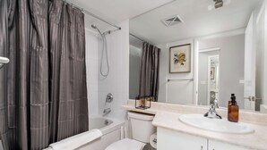 A modern bathroom with a bathtub, toilet, and sink. - Bright Waterfront Studio Steps to DT Toronto (Toronto)